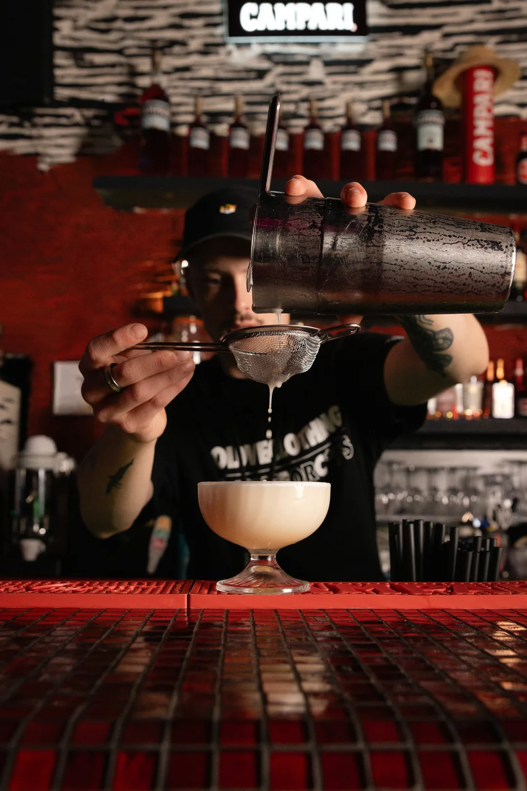 Ein Drink wird durch das Sieb in die Coupe abgeseiht