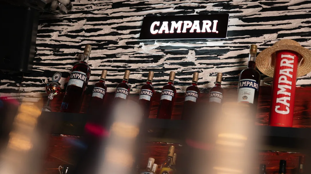 Das Regal mit Campari-Flaschen vor der Zebrawand