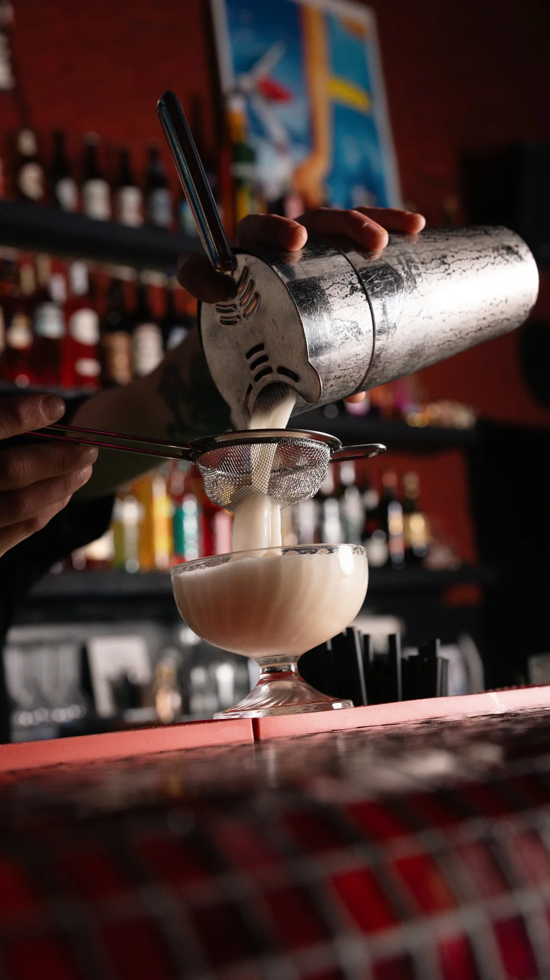 Ein Cocktail wird aus dem Shaker in eine Coupe gegossen